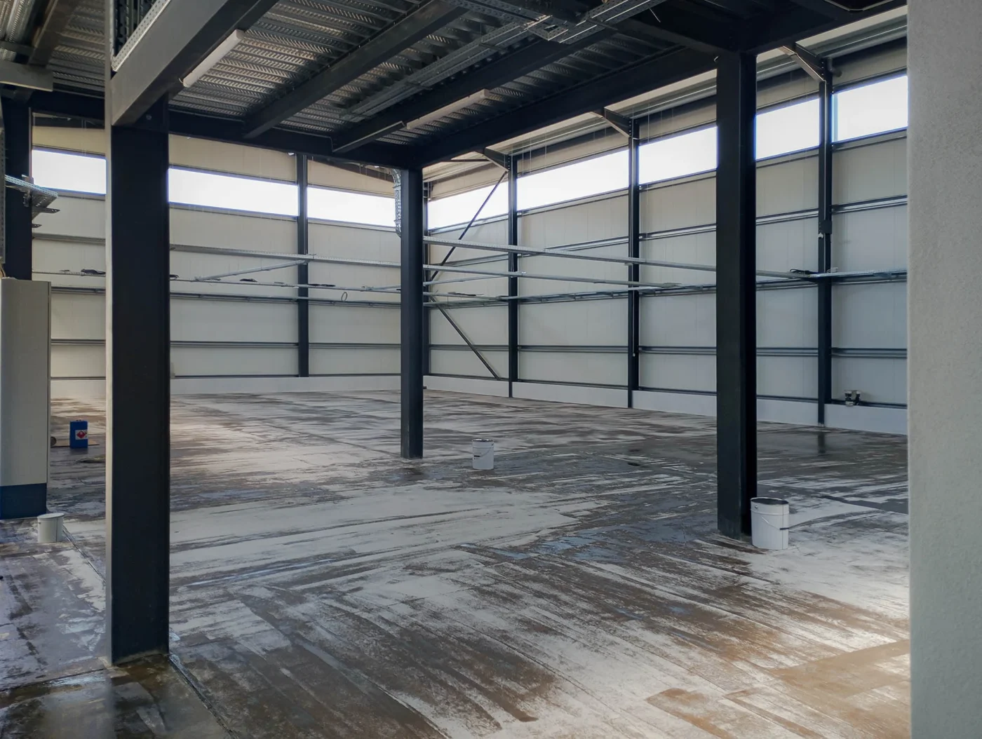 Nave industrial com estrutura metálica escura e pavimento epóxi cinzento