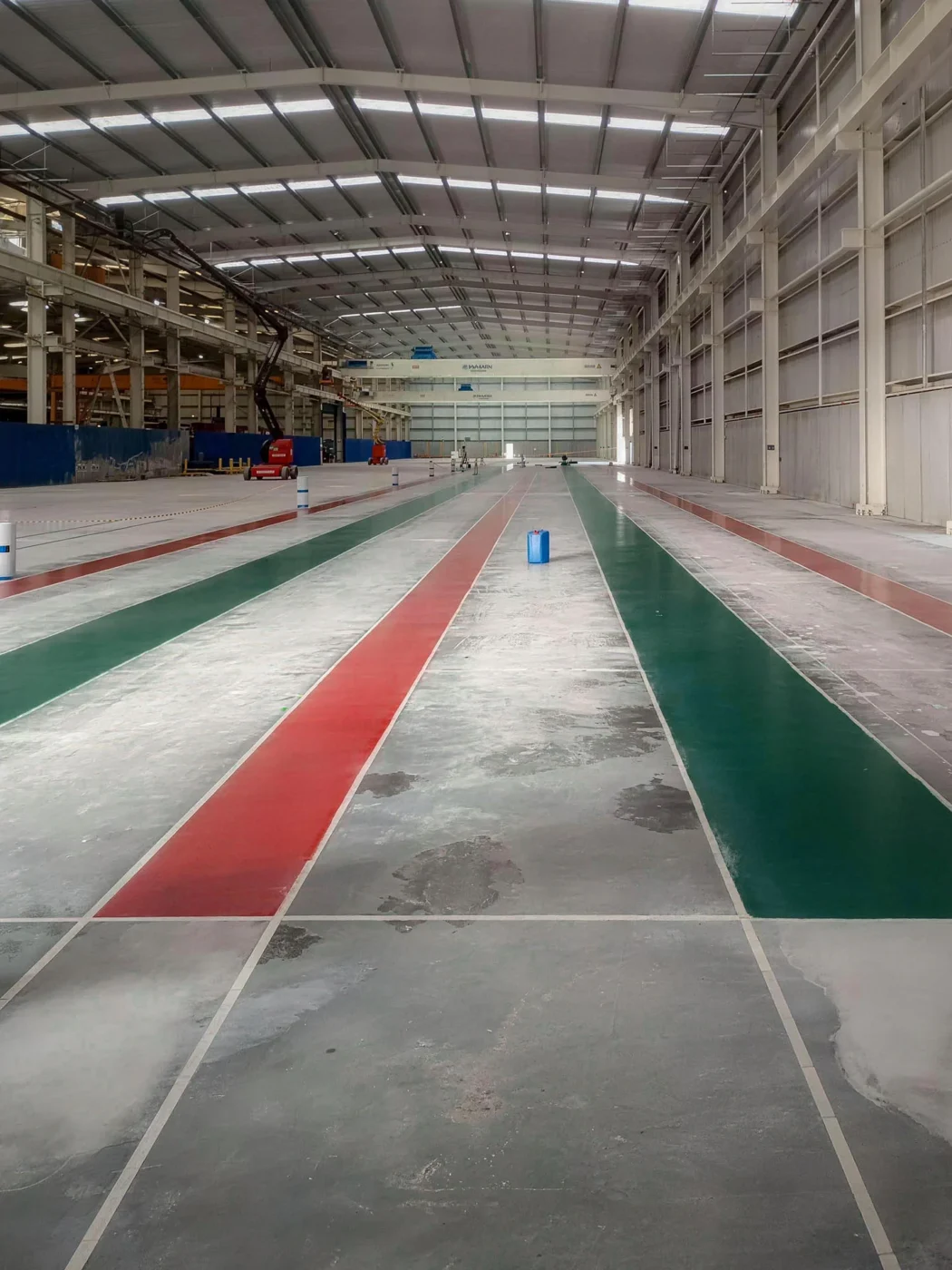 Corredores de circulação em epóxi verde e vermelho delimitados sobre pavimento de betão industrial